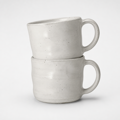 Dos mugs de gres blanco hueso apilados con esmalte moteado